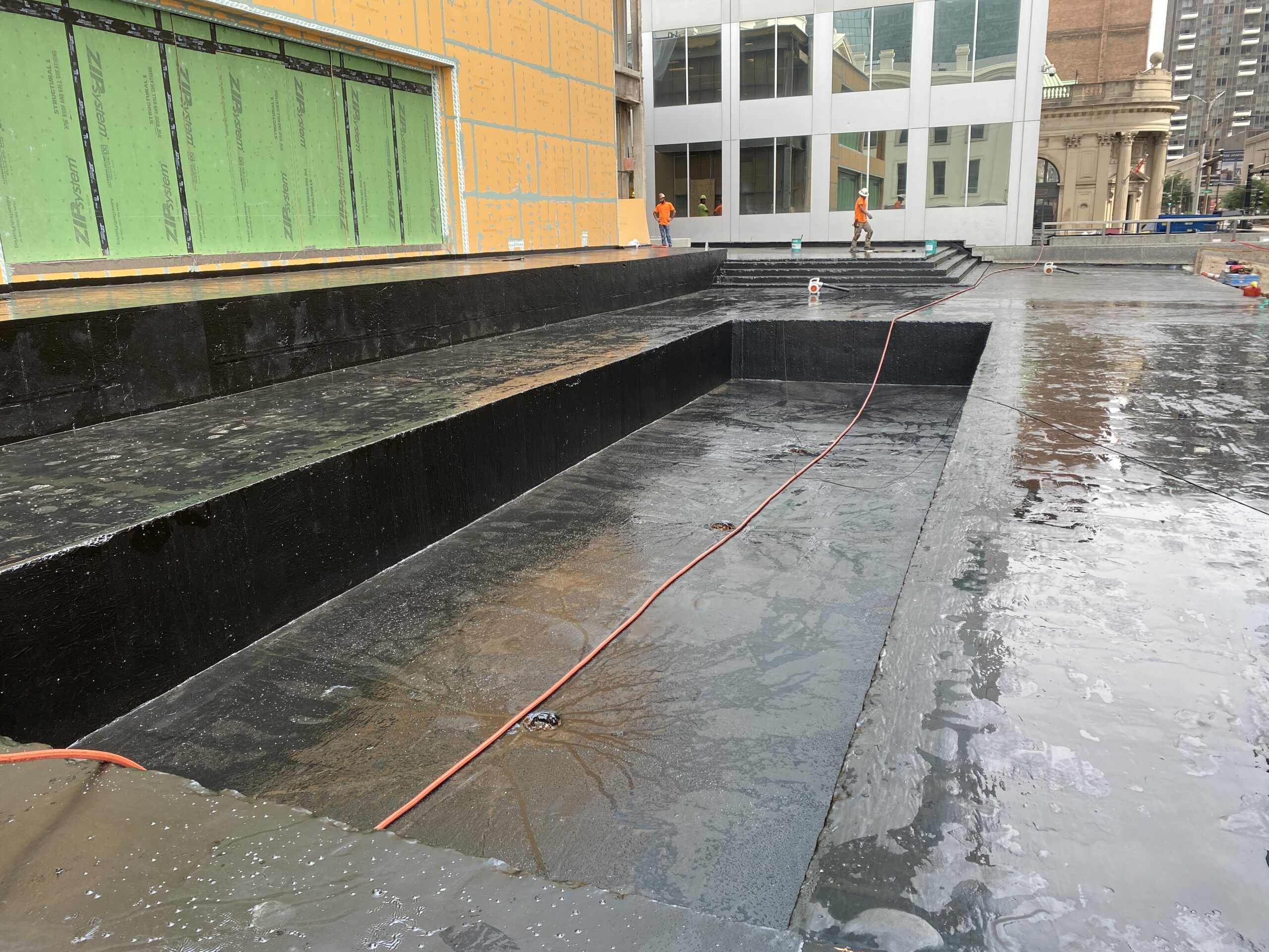 Waterproofing membrane on the deck and planter area at 100 North Broadway, wetted for electronic leak detection with the ground cable running across it.