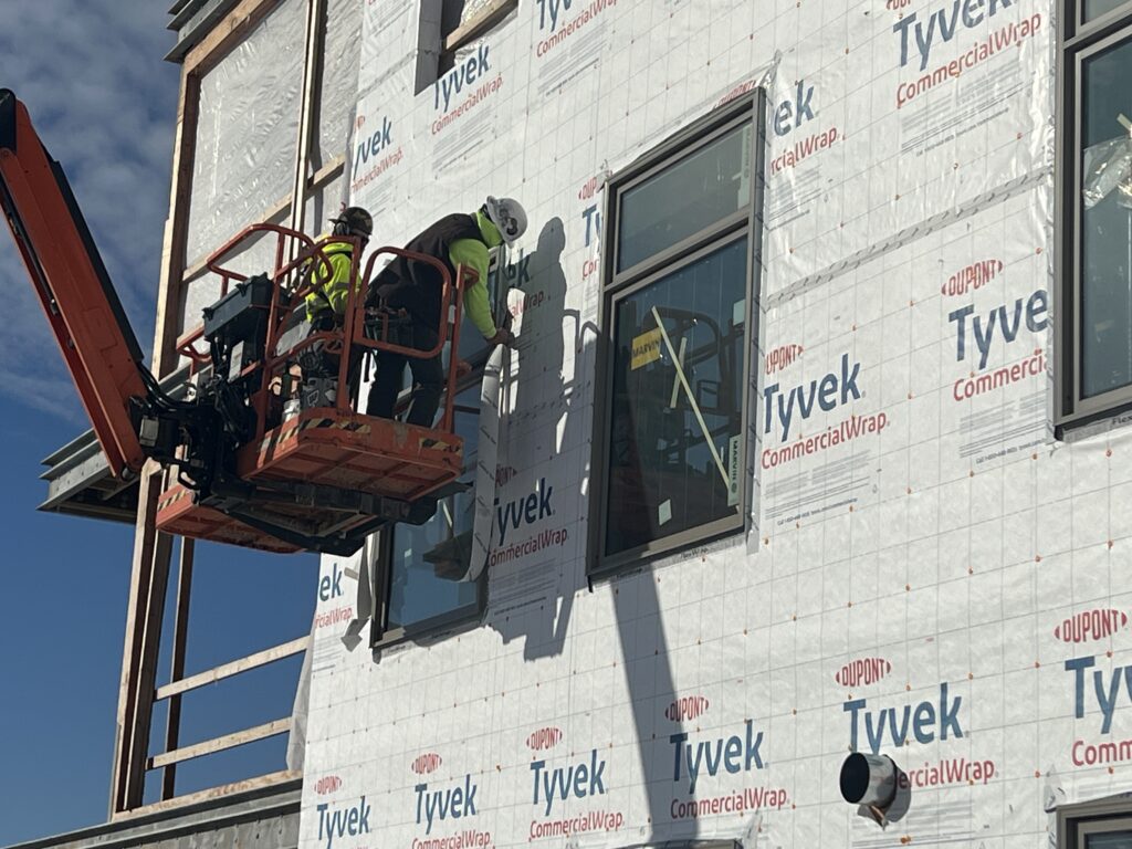G&W Team members on lift testing window enclosure on construction site