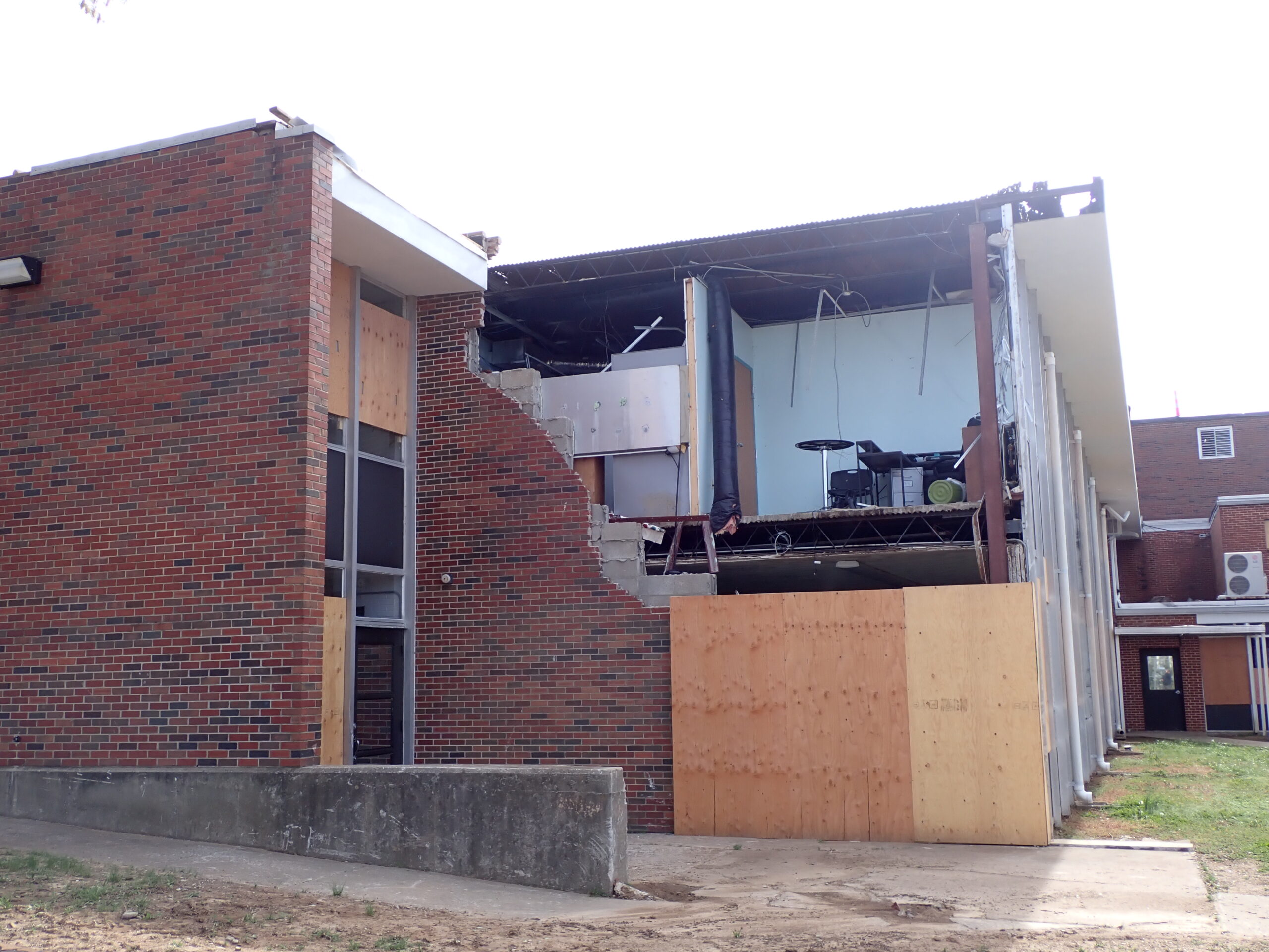 Exterior picture of commercial building with extensive damage to wall due to storm.