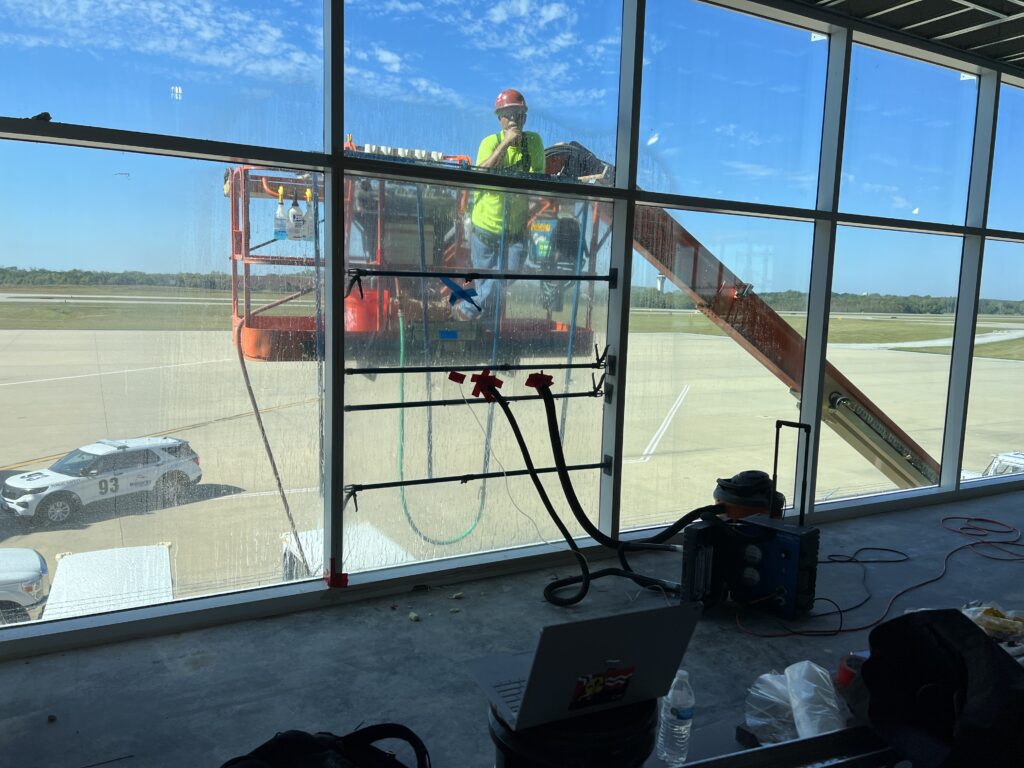 Air and water test setup on the curtainwall, with hoses and a manometer at an interior mullion and a lift positioned outside the glass.