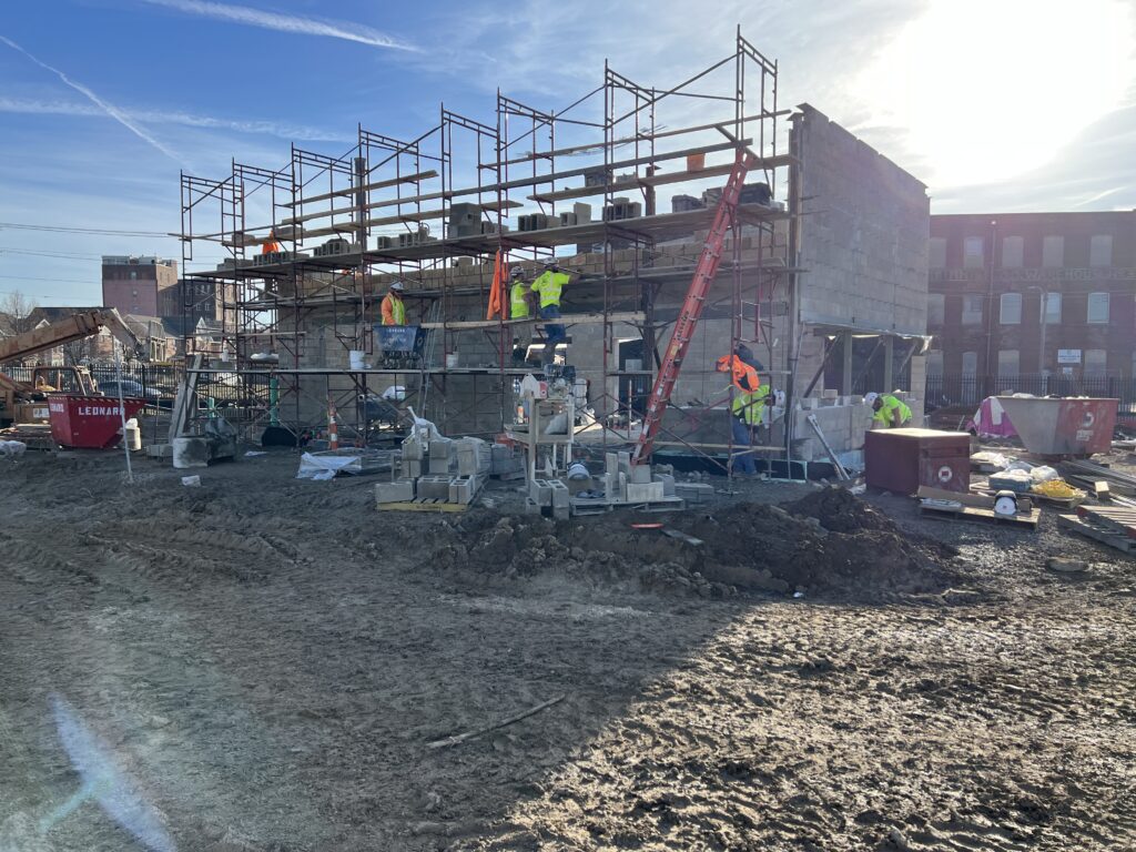Construction workers on frame of stone outbuilding