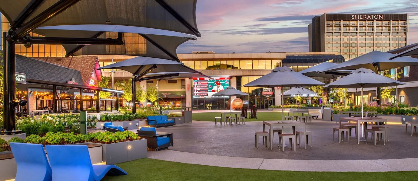 sunset view of an outdoor stone patio with circle tables and umbrellas