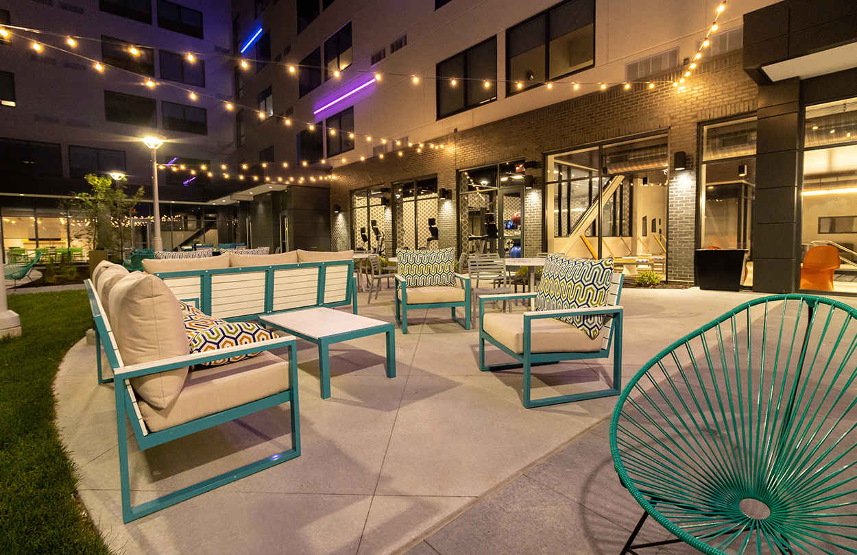 Lights strung over hotel patio outside sitting area with outdoor furniture