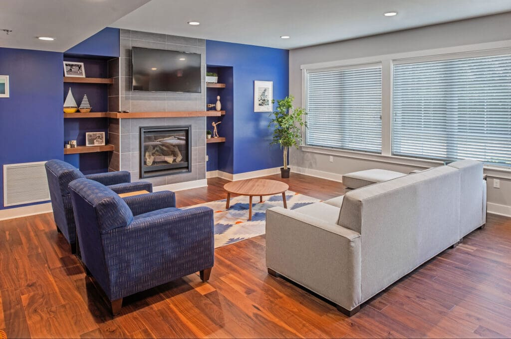 This contemporary living room features bold blue accent walls, rich hardwood floors, and a cozy fireplace with a tiled surround.
