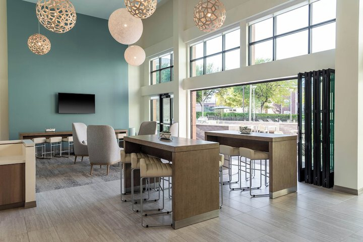 Lobby area with tables, chairs and windows in. hotel.