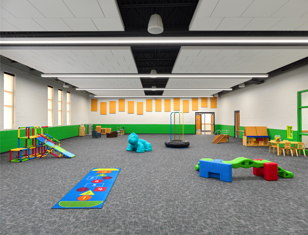 Open space playroom in early childhood center with colorful climbable toys and grey carpet