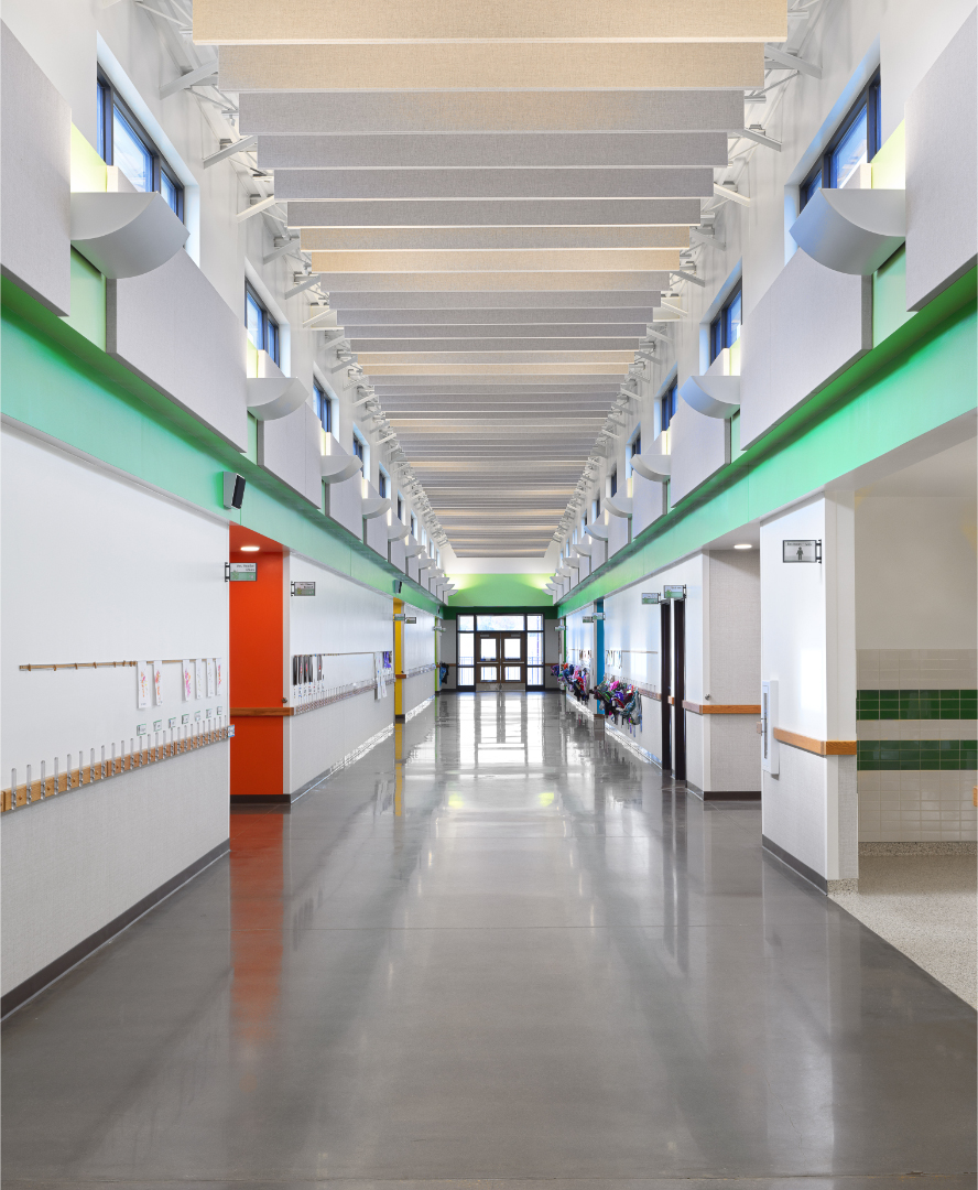 White walls with green trim and black floor in long elementary school hallway