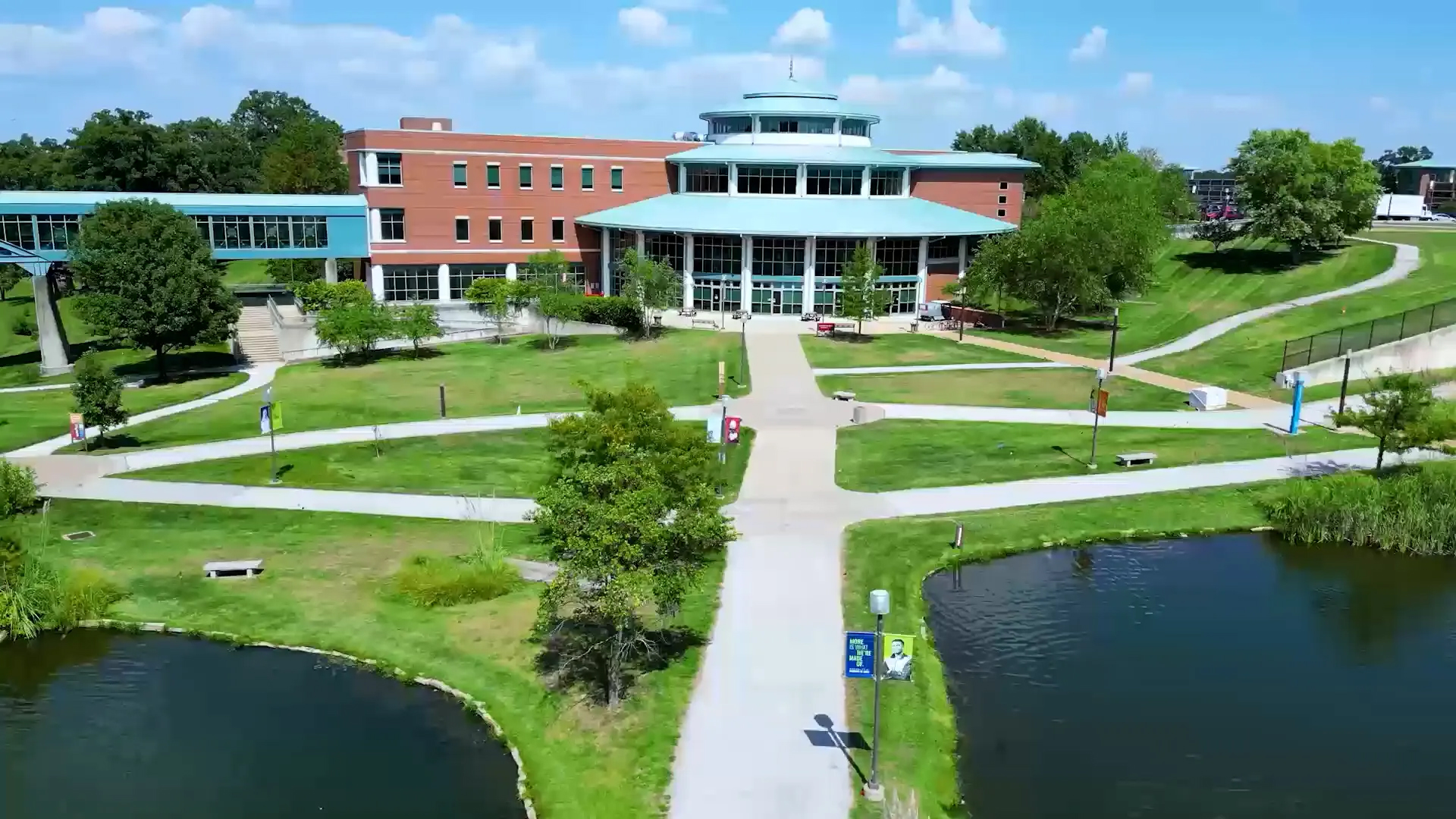 Aerial view of the Thomas Jefferson Library at the University of Missouri-St. Louis, with walkways leading past two ponds to the main entrance.
