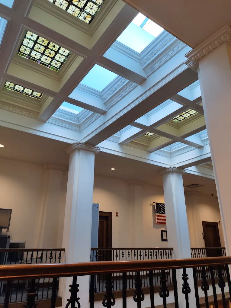 Restored stained-glass skylight and coffered ceiling above the columned second-floor landing at the Jefferson Court Building in Green Bay, Wisconsin.