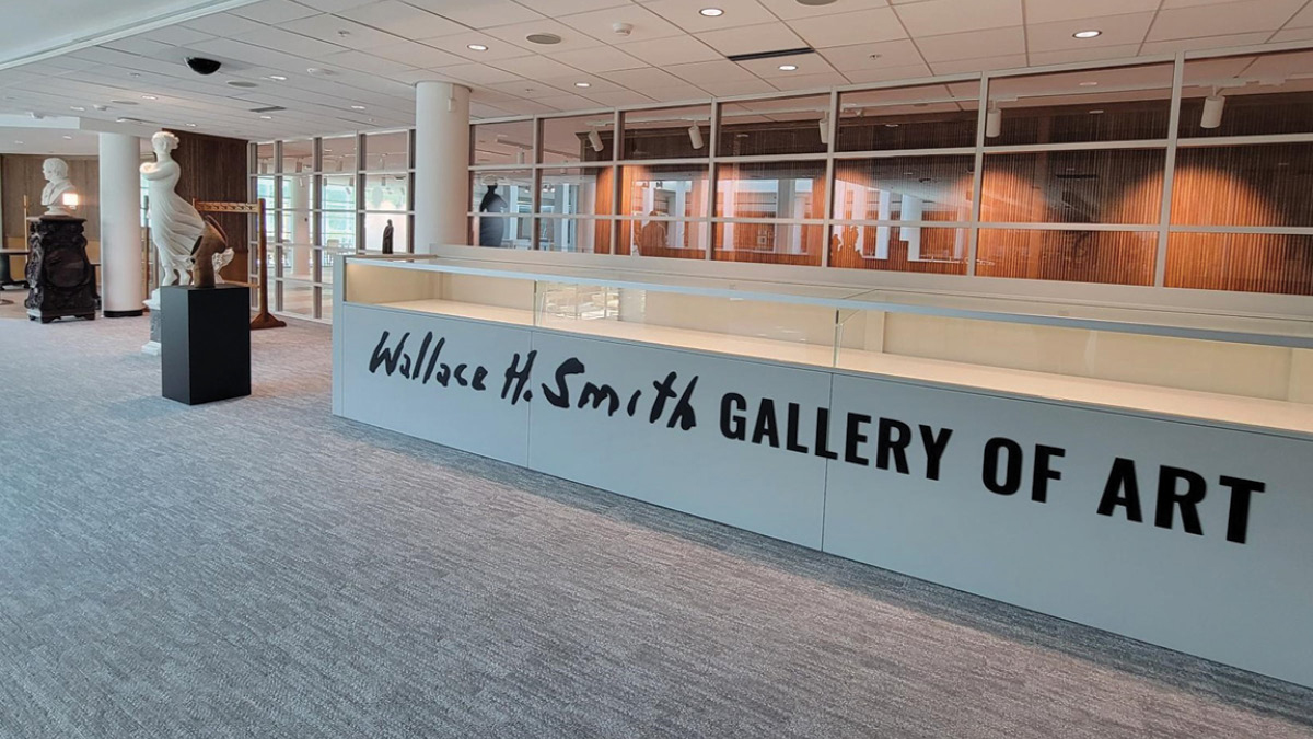 Entrance to the Wallace H. Smith Gallery of Art in the Mercantile Library, with marble sculptures and glass-walled reading rooms behind a long display case.