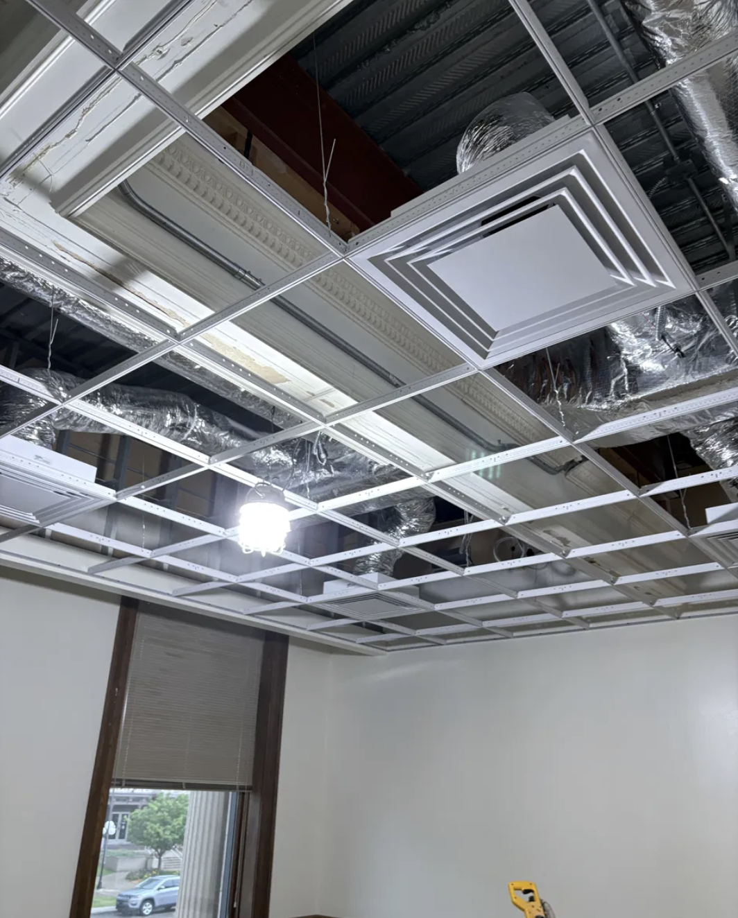 New HVAC diffuser and ceiling grid installed alongside original crown molding during the Jefferson Court Building renovation.