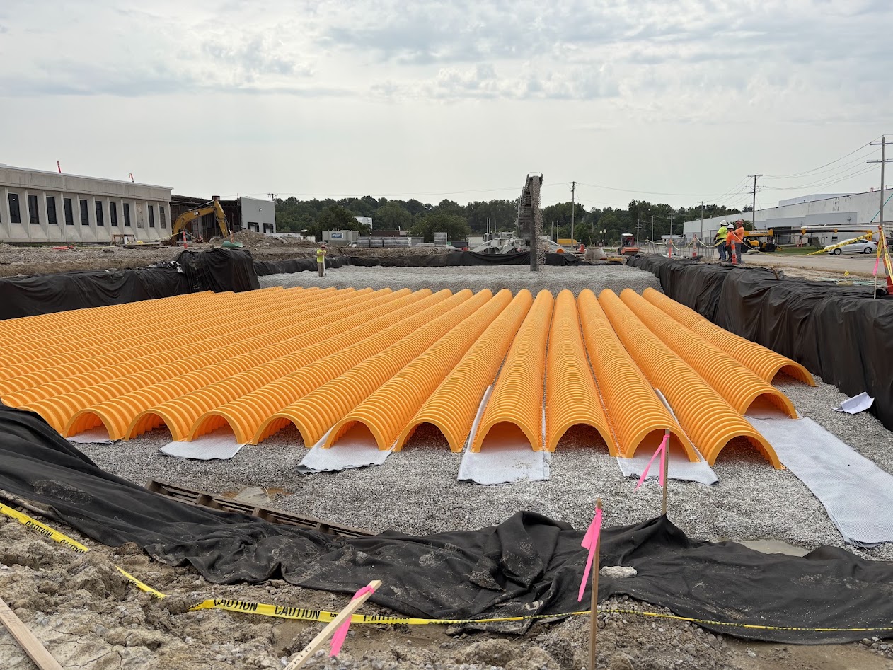Rows of orange arch stormwater chambers set on a stone bed during underground detention installation at the Enterprise loading dock project.